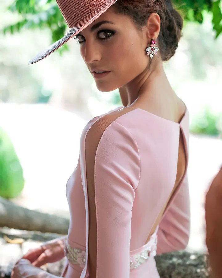 Femme en robe noire satinée, ceinture, bas résille, devant porte blanche