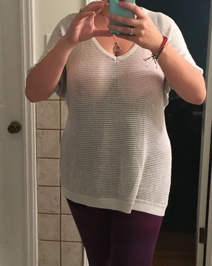 Femme en tenue blanche, prenant un selfie devant miroir, mains autour du téléphone