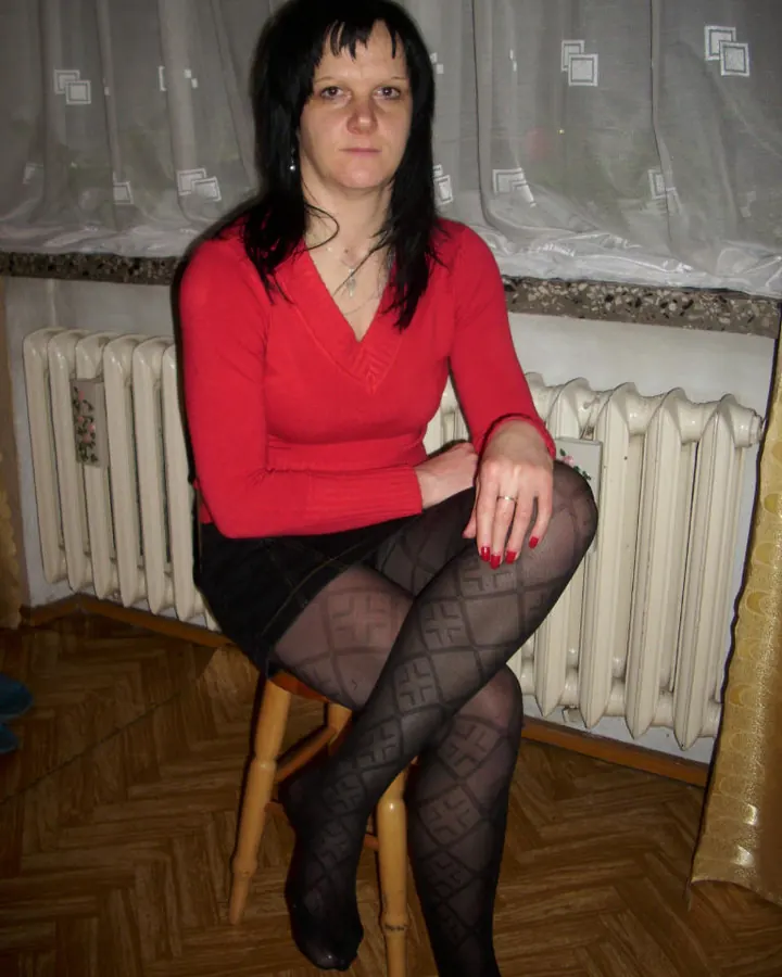 Femme en lingerie rose et blanche, avec des cheveux longs ondulés, posant devant un fond rose, tenant un voile rose.